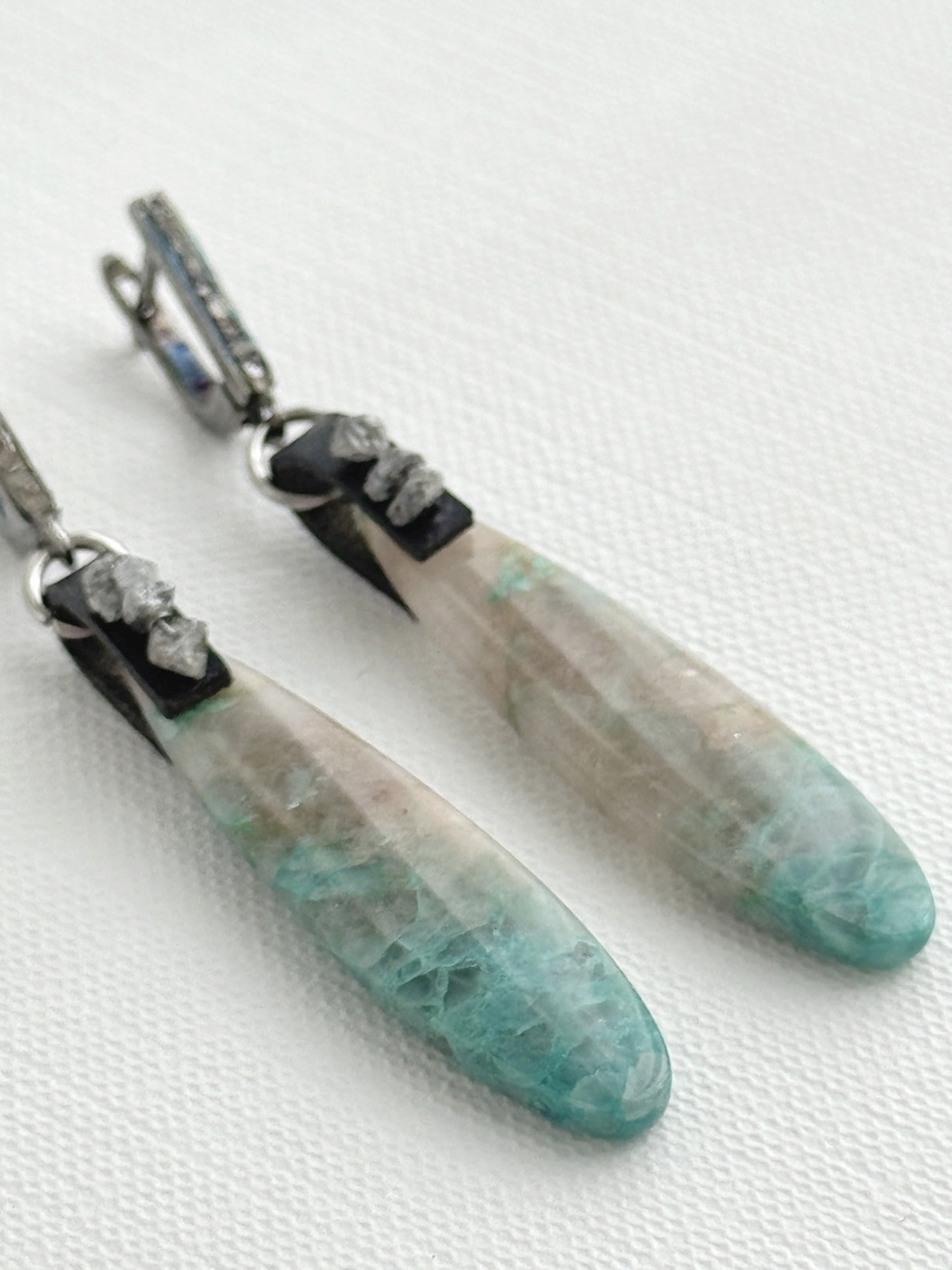 Chrysocolla in quartz teardrop earrings with raw grey diamonds on black leather and oxidized sterling silver pavé leverbacks, close-up