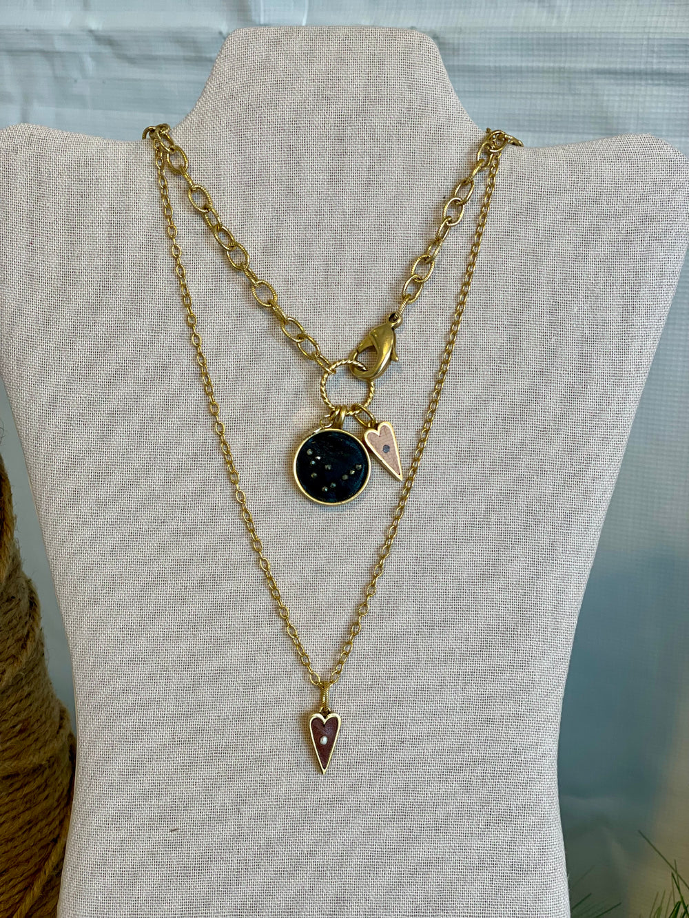 Two layered necklaces showing the front clasp and charm attachments