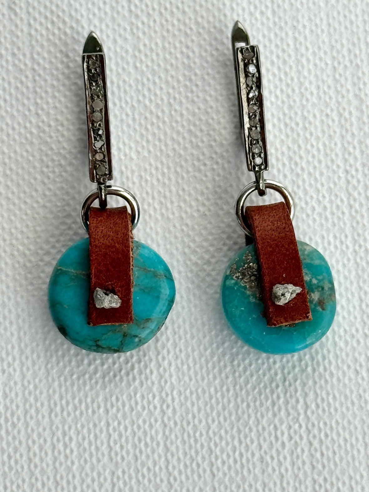Arizona turquoise coin earrings with a hand-sewn raw grey diamond on chestnut brown leather and oxidized sterling pavé diamond leverbacks, front view