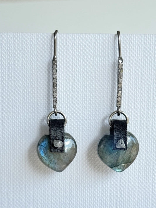 Puffy labradorite heart earrings with a hand-sewn raw grey diamond on black leather, hanging from long oxidized sterling pavé diamond bar hooks, front view