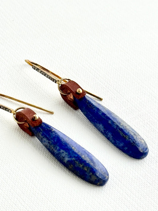 Lapis lazuli teardrop earrings lying angled, brown leather, gold bead, pave diamond hooks