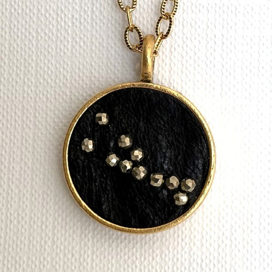 Taurus zodiac constellation charm — black leather with hand-sewn pyrite beads, gold setting, on a fine cable link chain necklace