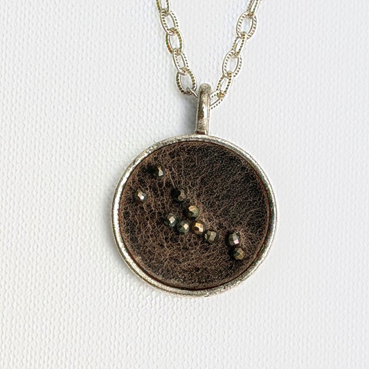 Taurus zodiac constellation charm — Grey Ghost leather with hand-sewn pyrite beads, silver setting, on a fine cable link chain necklace